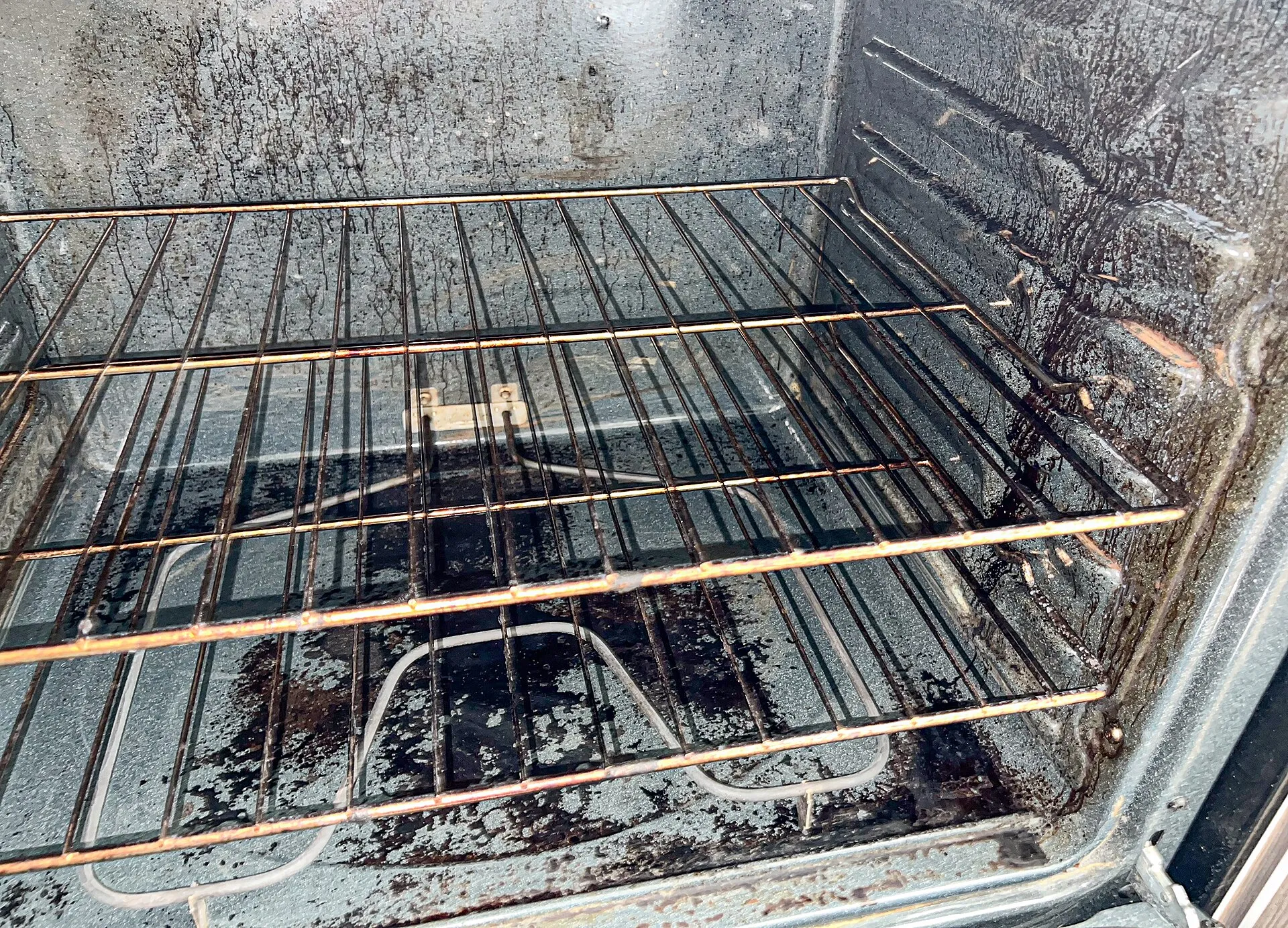 Ugn med fastbränt fett och sot på väggarna och under gallret